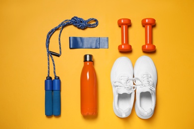 Photo of Flat lay composition with sports accessories on orange background