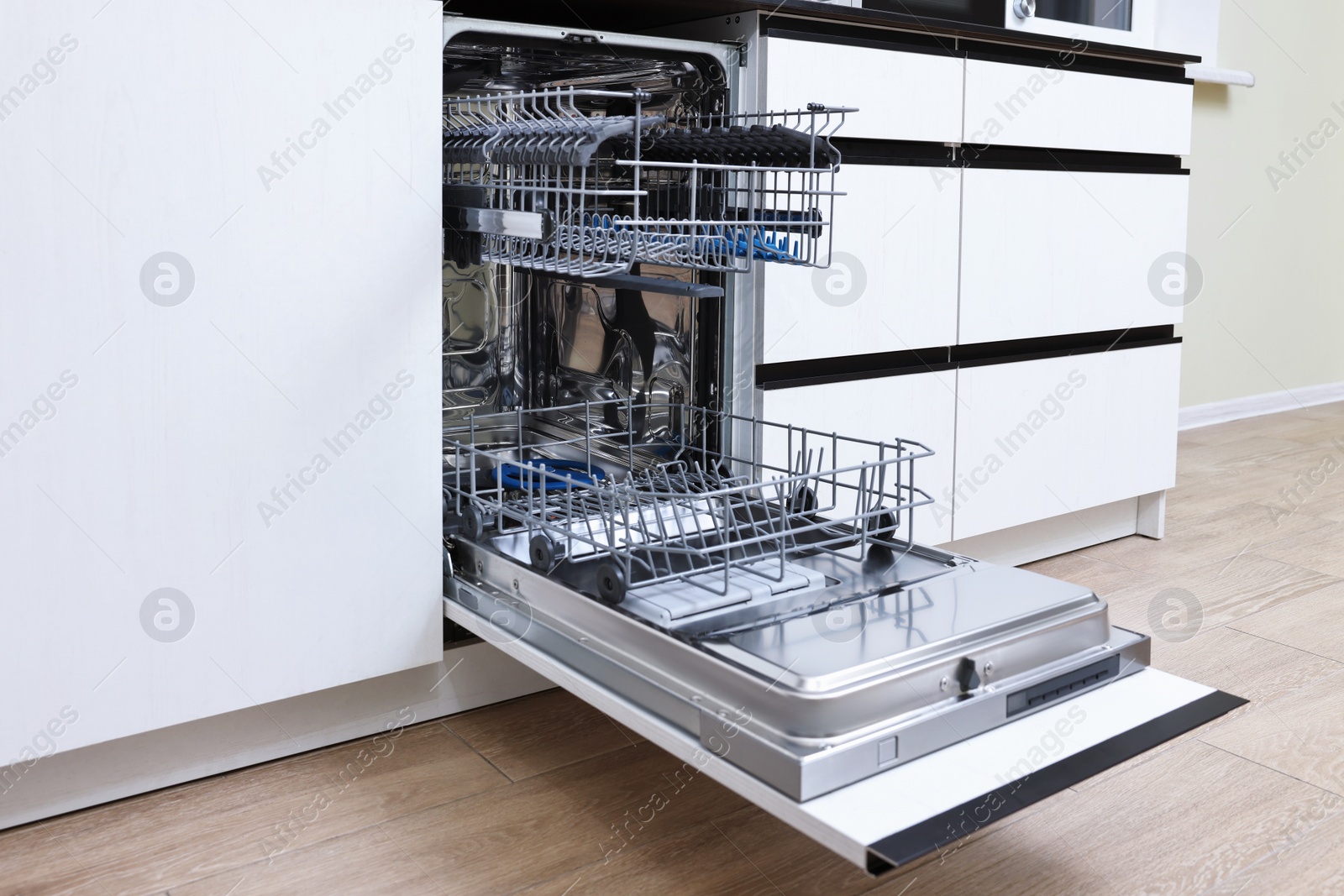 Photo of Open clean empty dishwasher in kitchen. Home appliance