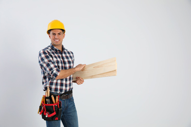 Handsome carpenter with wooden planks on light background. Space for text