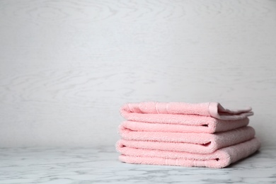 Stack of soft bath towels on table. Space for text