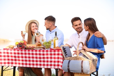 Photo of Young happy people at picnic table outdoors