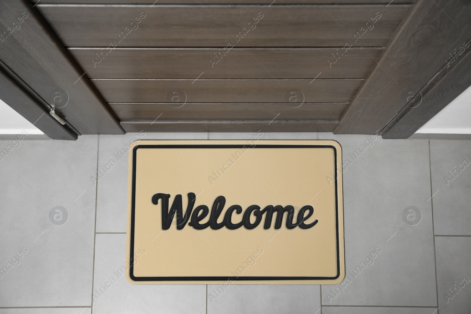 Photo of Beautiful beige doormat with word Welcome on floor near entrance, top view