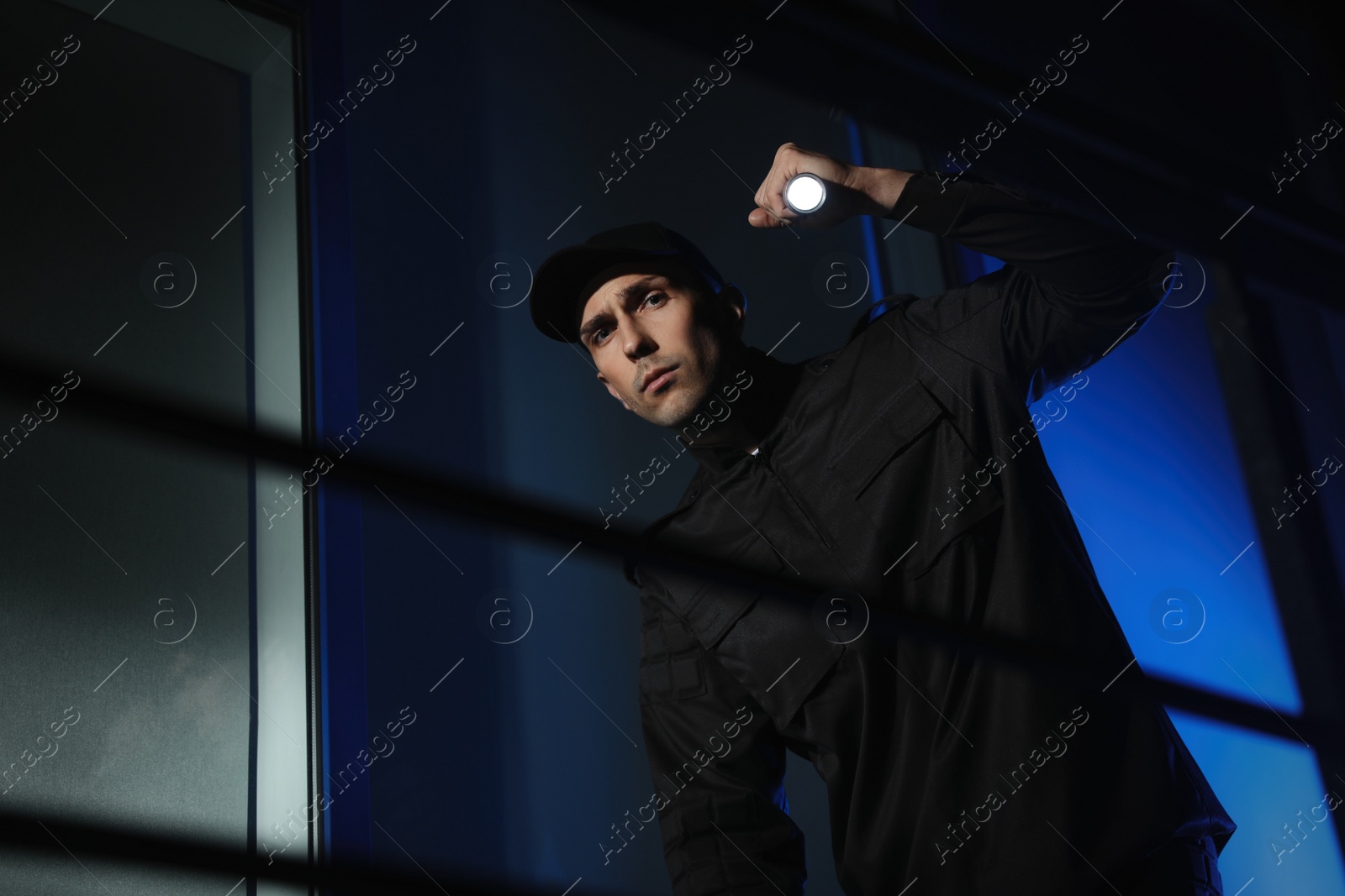 Photo of Male security guard with flashlight in dark room