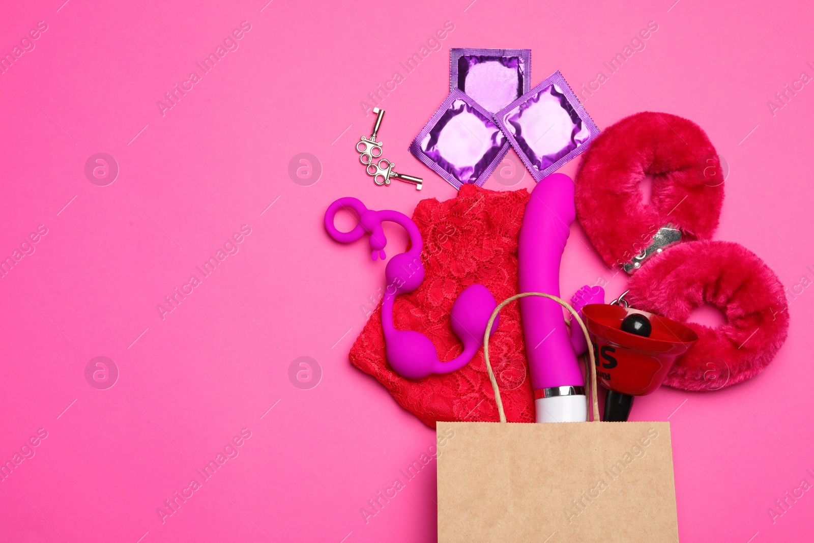 Photo of Shopping bag and different sex toys on pink background, flat lay. Space for text