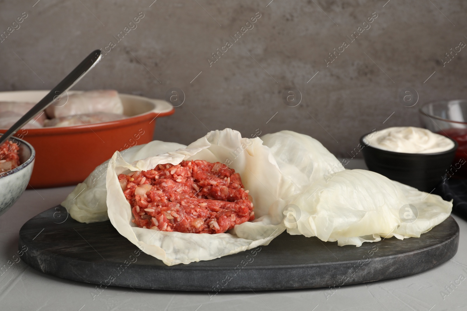 Photo of Preparing stuffed cabbage rolls on grey table