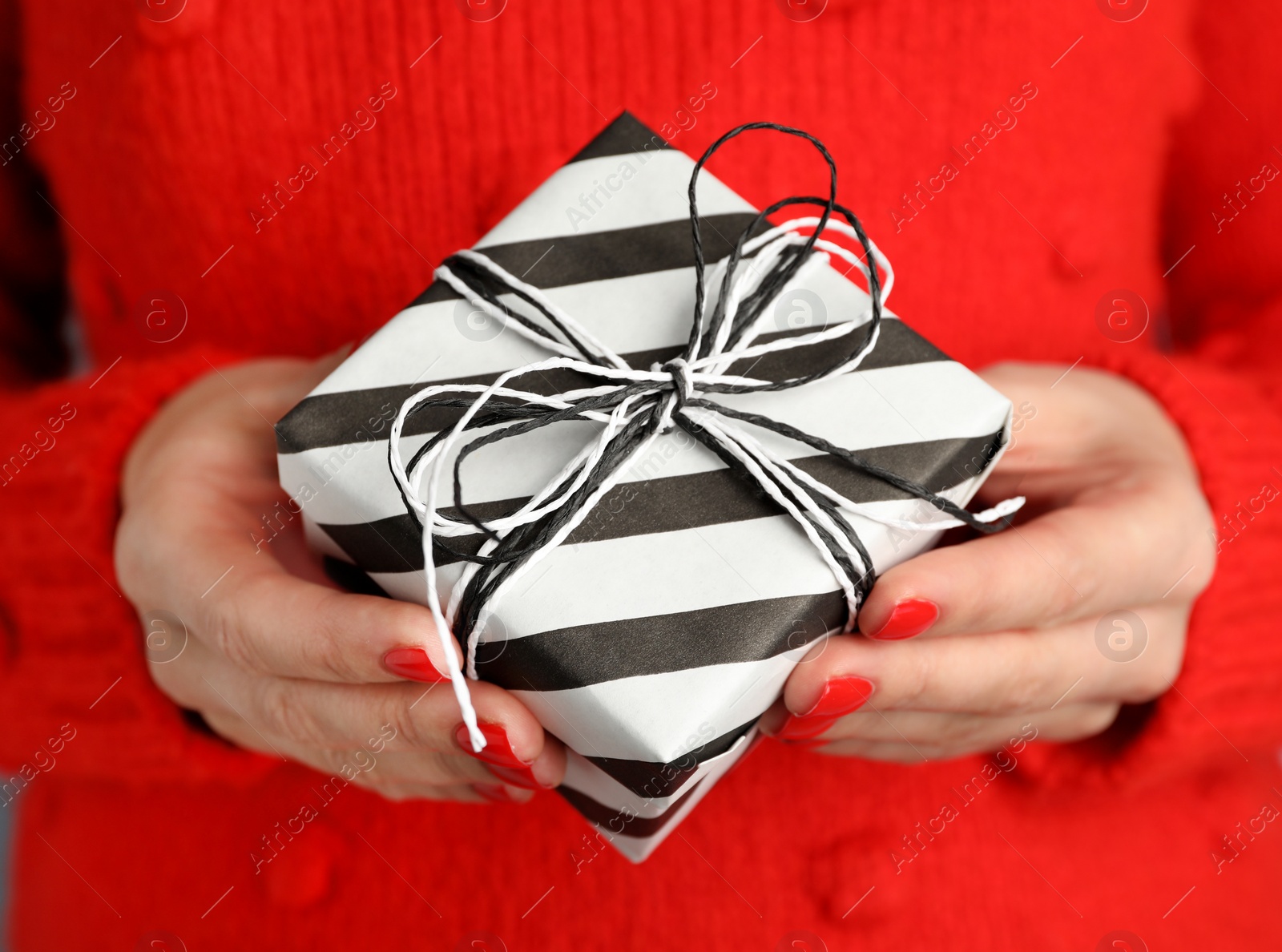 Photo of Young woman holding Christmas gift, closeup view