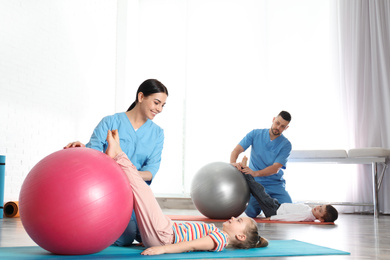 Orthopedists working with little children in hospital gym