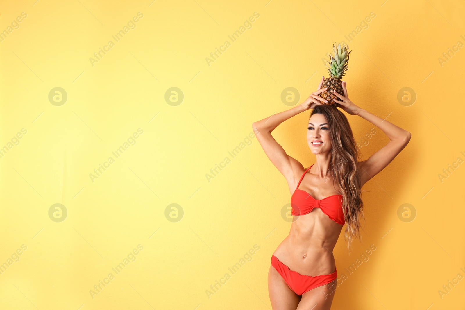 Photo of Pretty sexy woman in stylish bikini with pineapple on color background, space for text