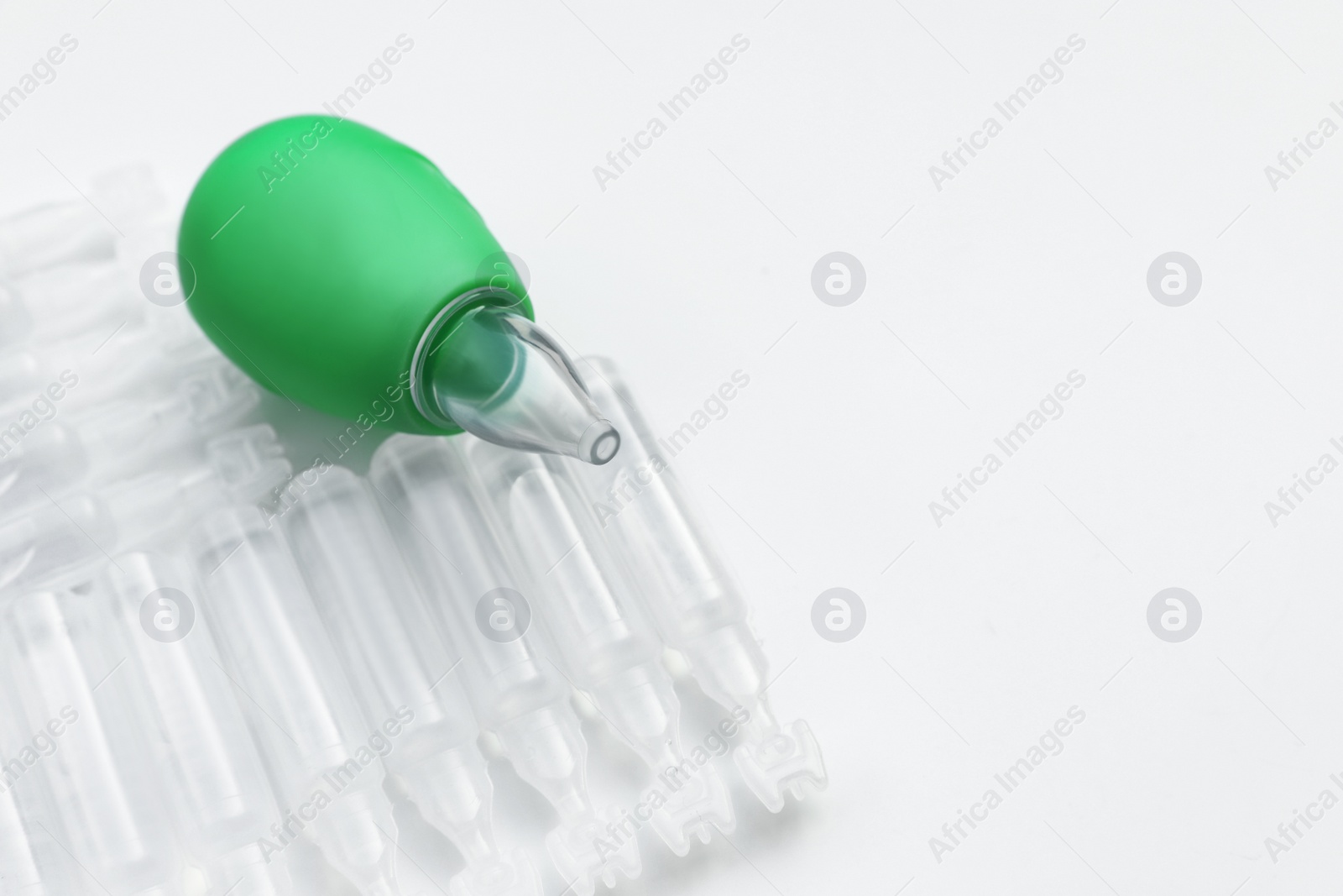 Photo of Single dose ampoules of sterile isotonic sea water solution and nasal aspirator on white background, closeup. Space for text