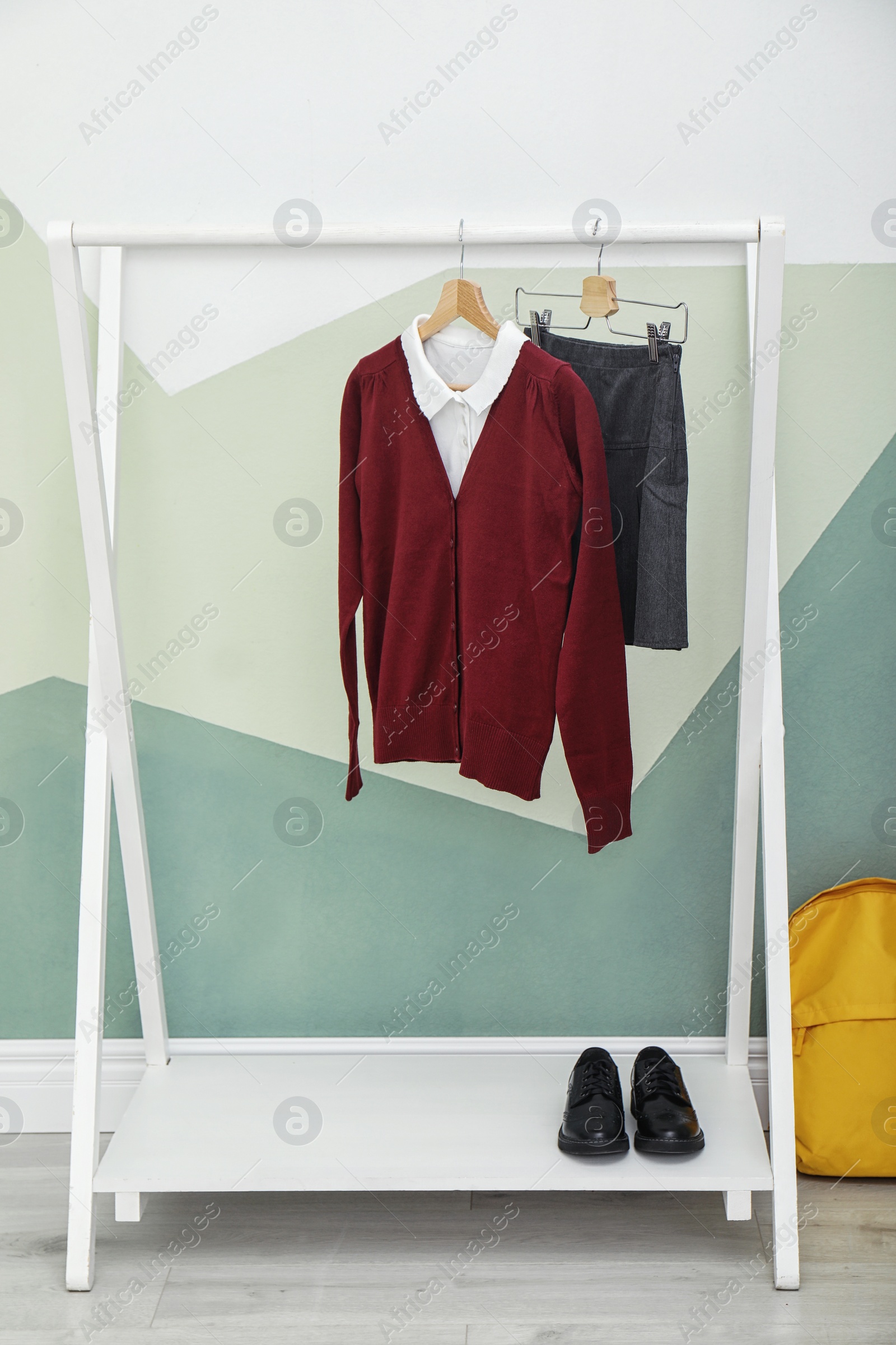 Photo of School uniform for girl on rack near color wall