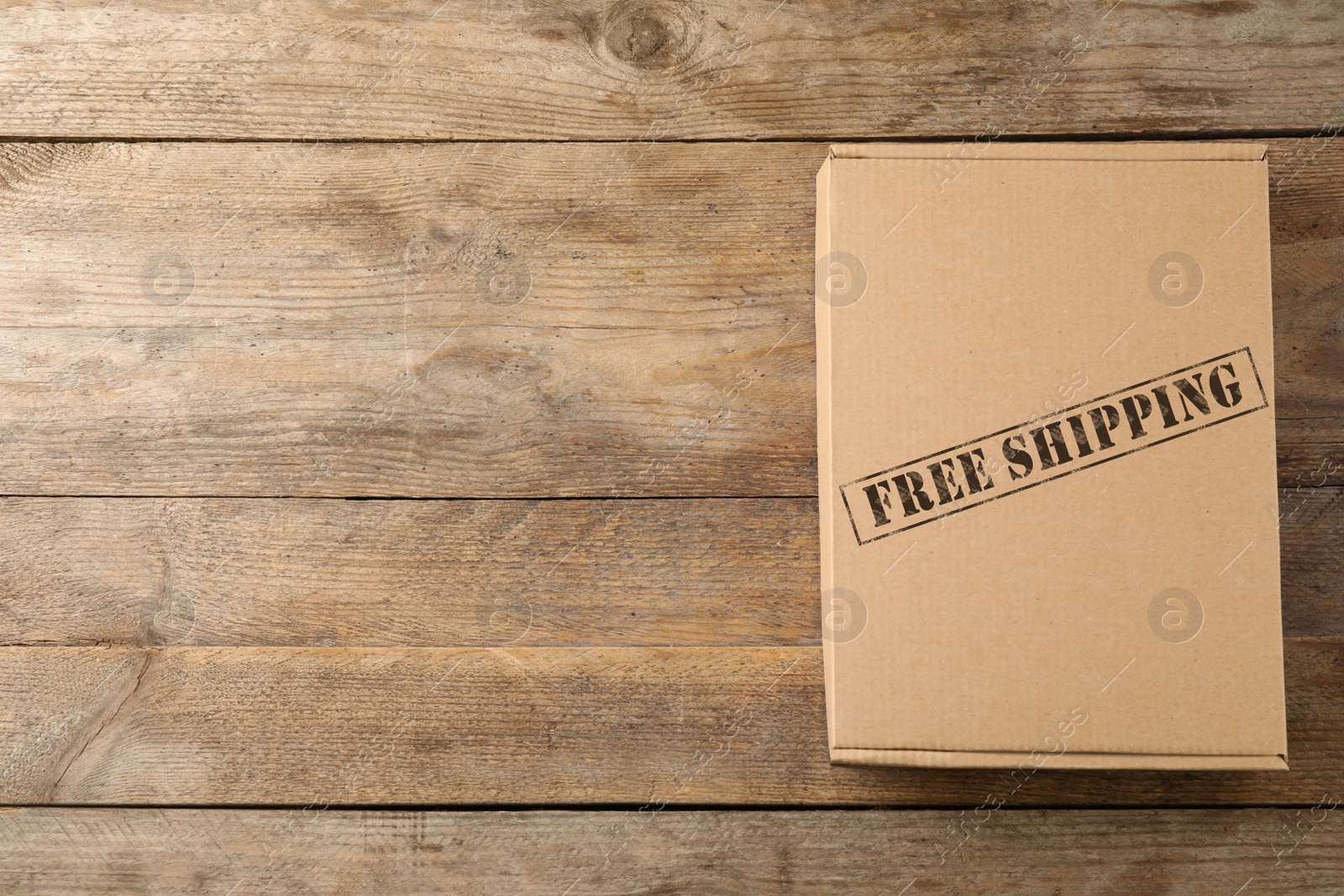 Image of Closed cardboard box on wooden background, top view with space for text. Free shipping