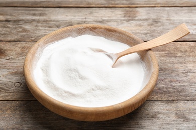 Photo of Plate with baking soda on wooden background