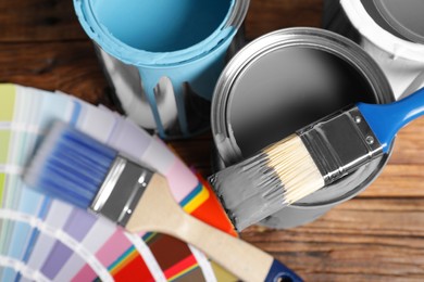 Cans of paints, brushes and color palette on wooden background, flat lay