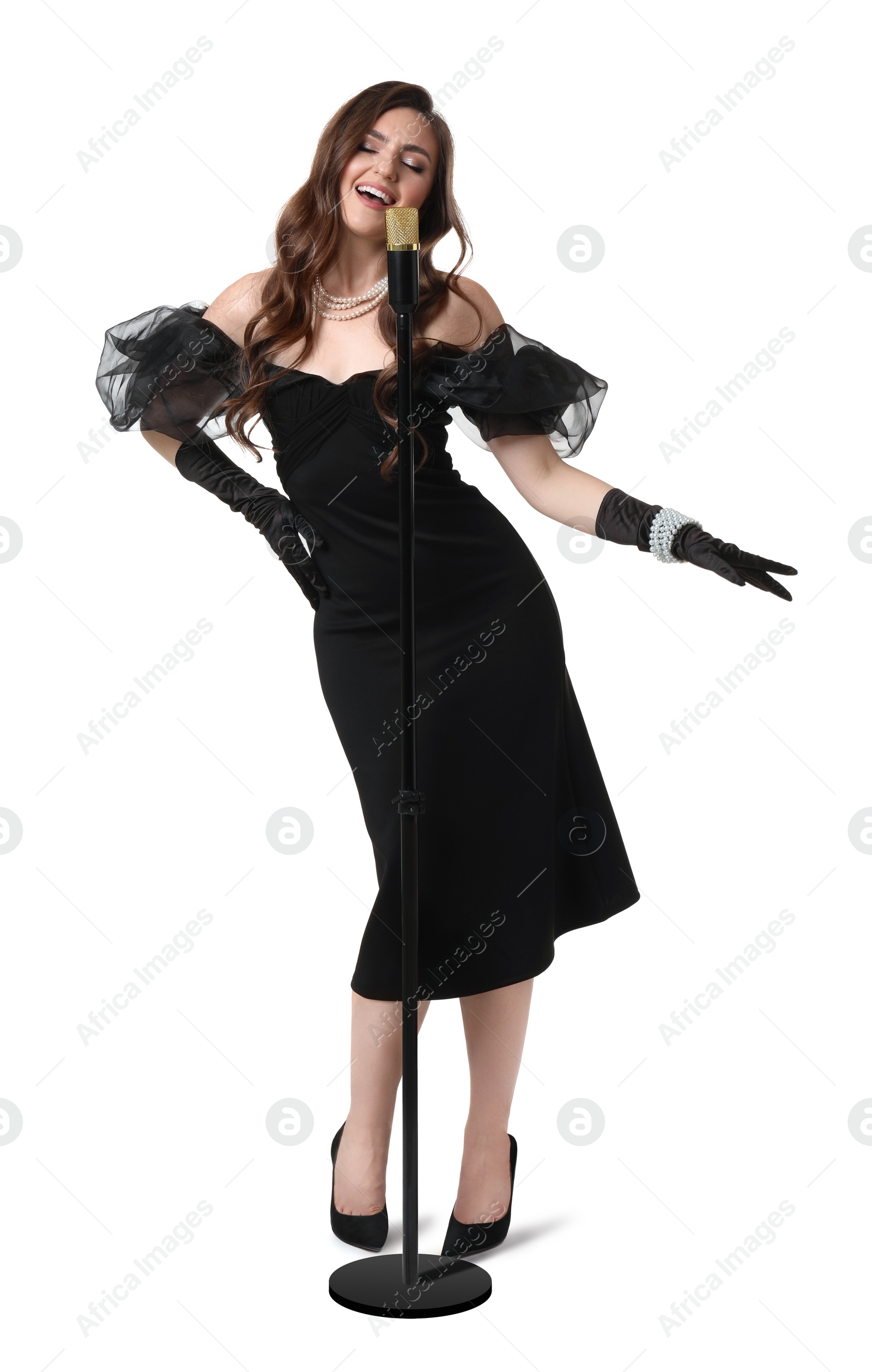 Photo of Beautiful young woman in stylish black dress with microphone singing on white background