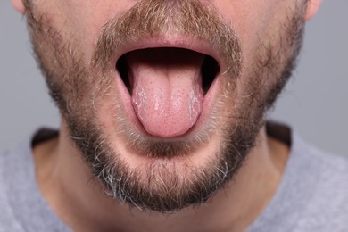 Closeup view of man showing his tongue on grey background