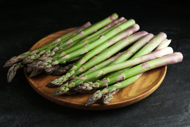 Photo of Fresh raw asparagus on black table, closeup