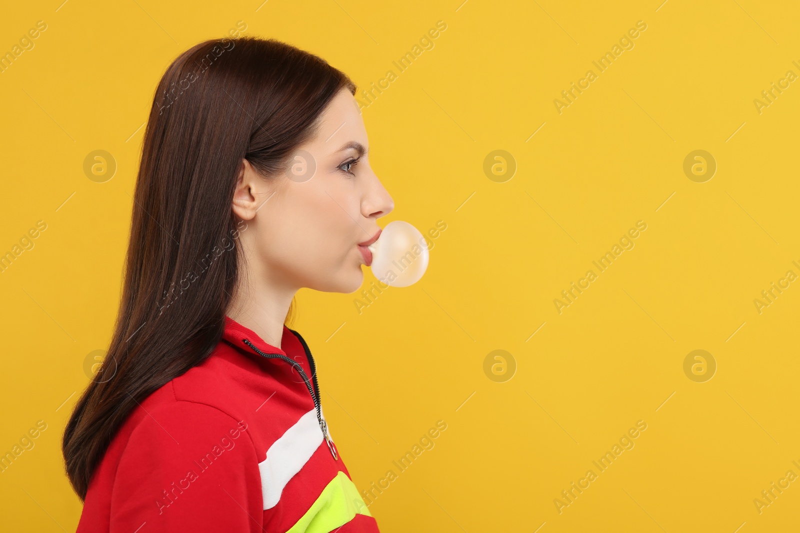 Photo of Beautiful woman blowing bubble gum on orange background, space for text