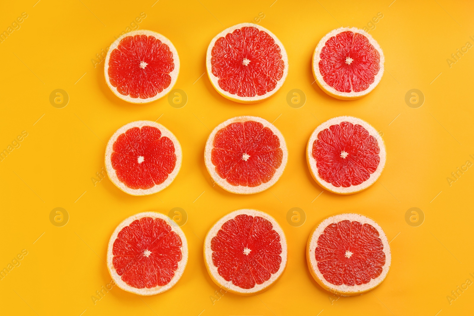 Photo of Flat lay composition with tasty ripe grapefruit slices on orange background