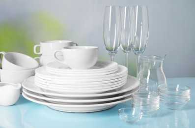 Set of clean dishes and glasses on light blue table