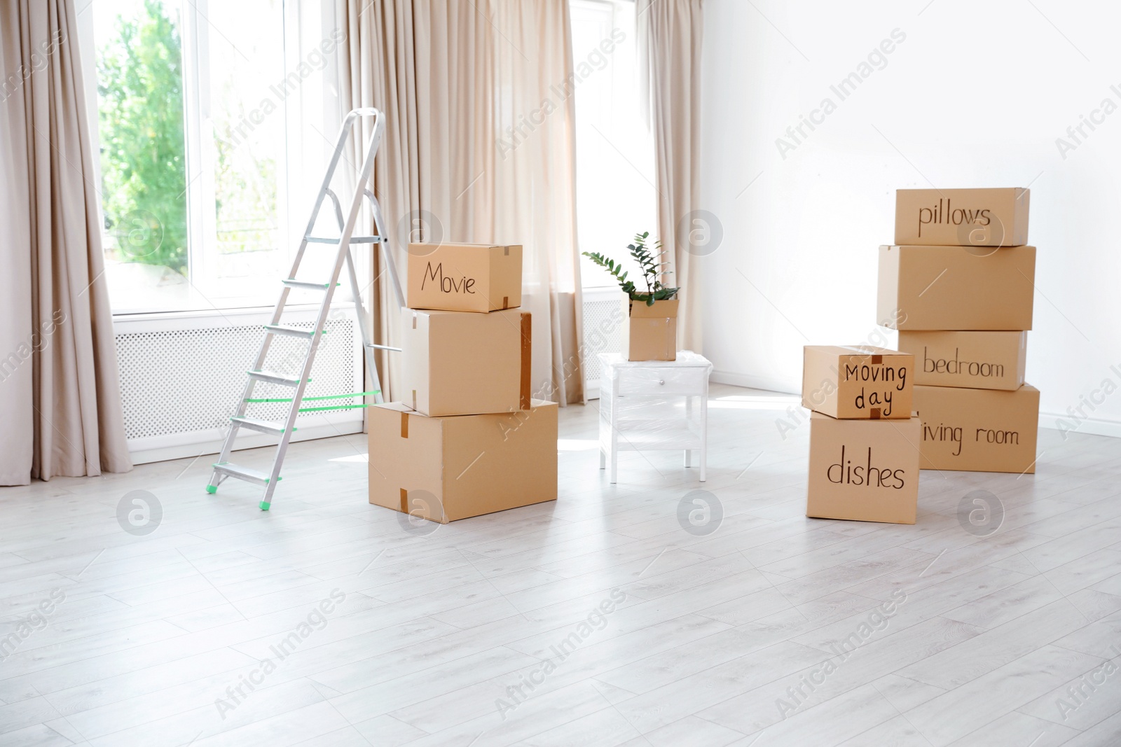 Photo of Ladder and cardboard boxes in empty room. Moving day