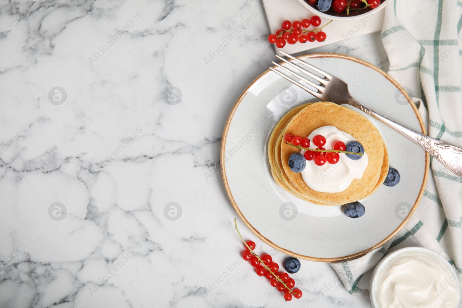 Photo of Pancakes with natural yogurt, blueberries and red currants on white marble table, flat lay. Space for text