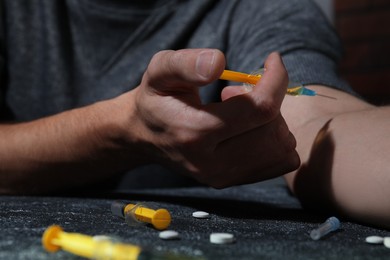 Addicted man taking drugs at black textured table, closeup
