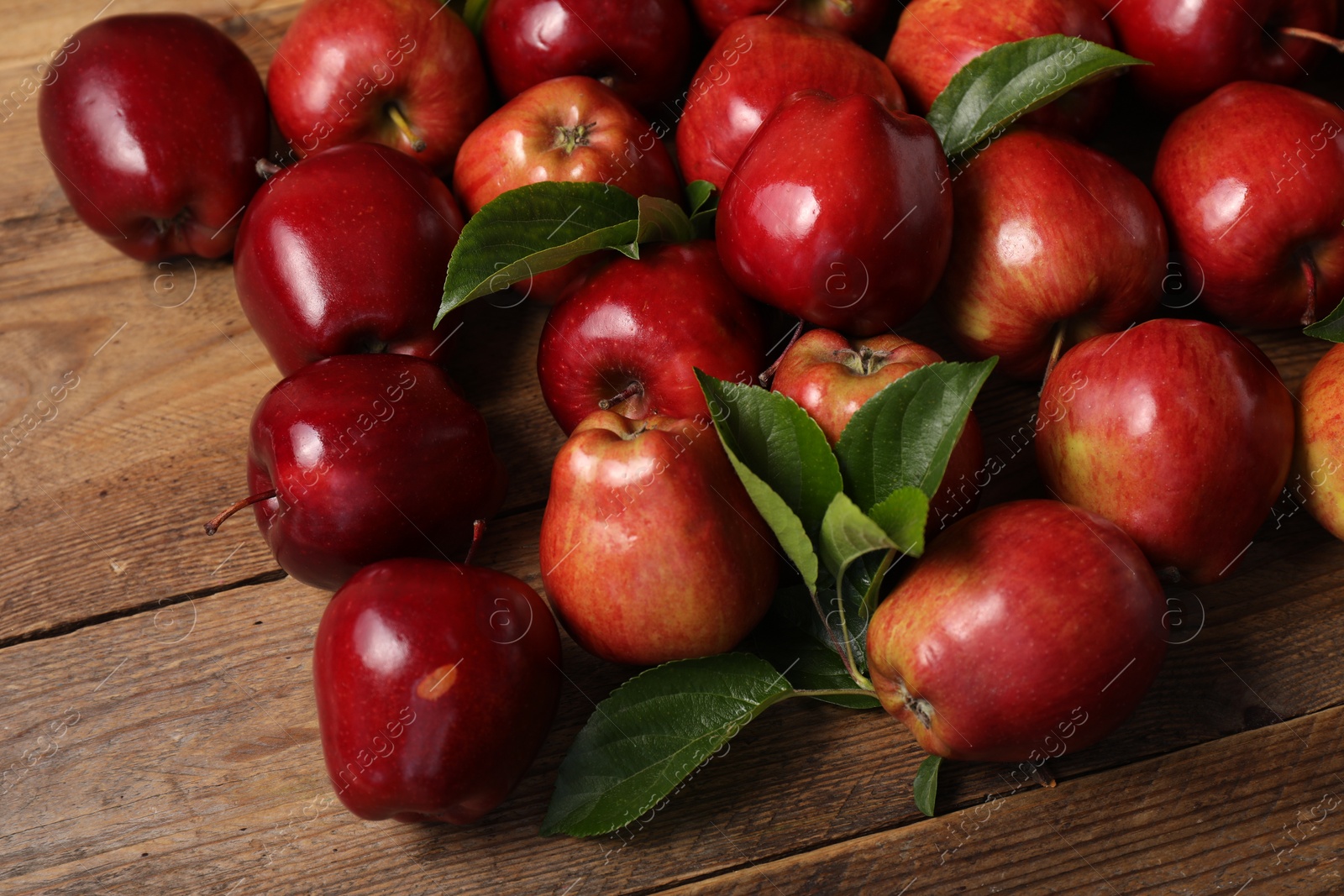 Photo of Fresh ripe red apples with leaves on wooden table