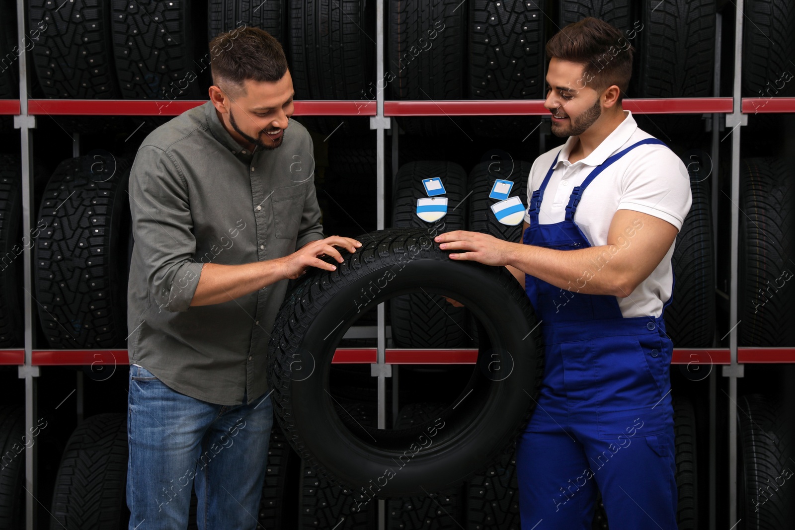 Photo of Mechanic helping client to choose car tire in auto store