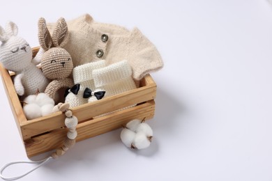 Different baby accessories and clothes in wooden crate on white background. Space for text