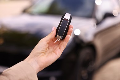 Photo of Woman holding car flip key near her vehicle outdoors, closeup