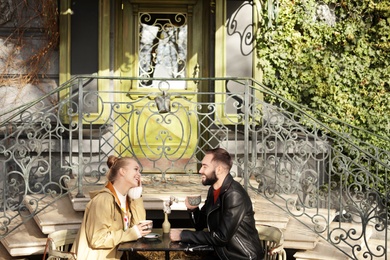 Lovely young couple enjoying tasty coffee at table outdoors