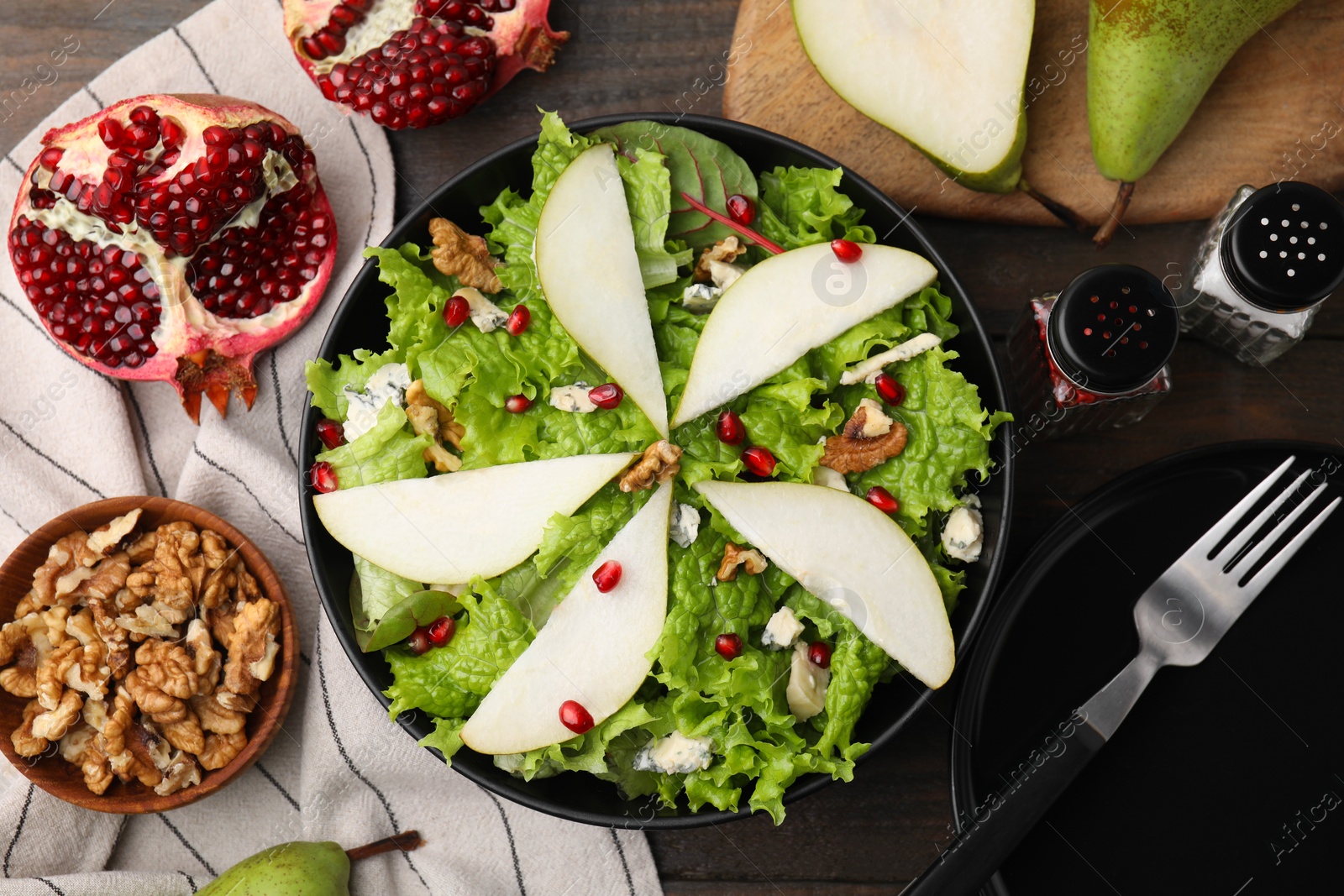 Photo of Delicious pear salad in bowl served on wooden table, flat lay