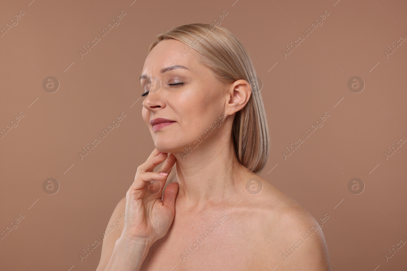 Photo of Beautiful woman touching her neck on beige background