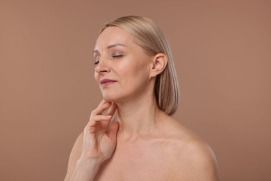 Beautiful woman touching her neck on beige background