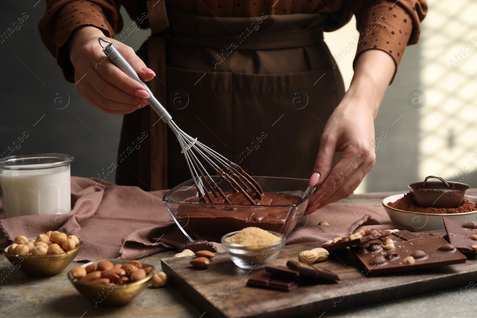 Photo of Woman mixing delicious chocolate cream with whisk at table, closeup