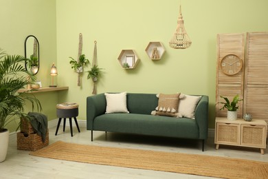 Photo of Living room with comfortable green sofa. Interior design