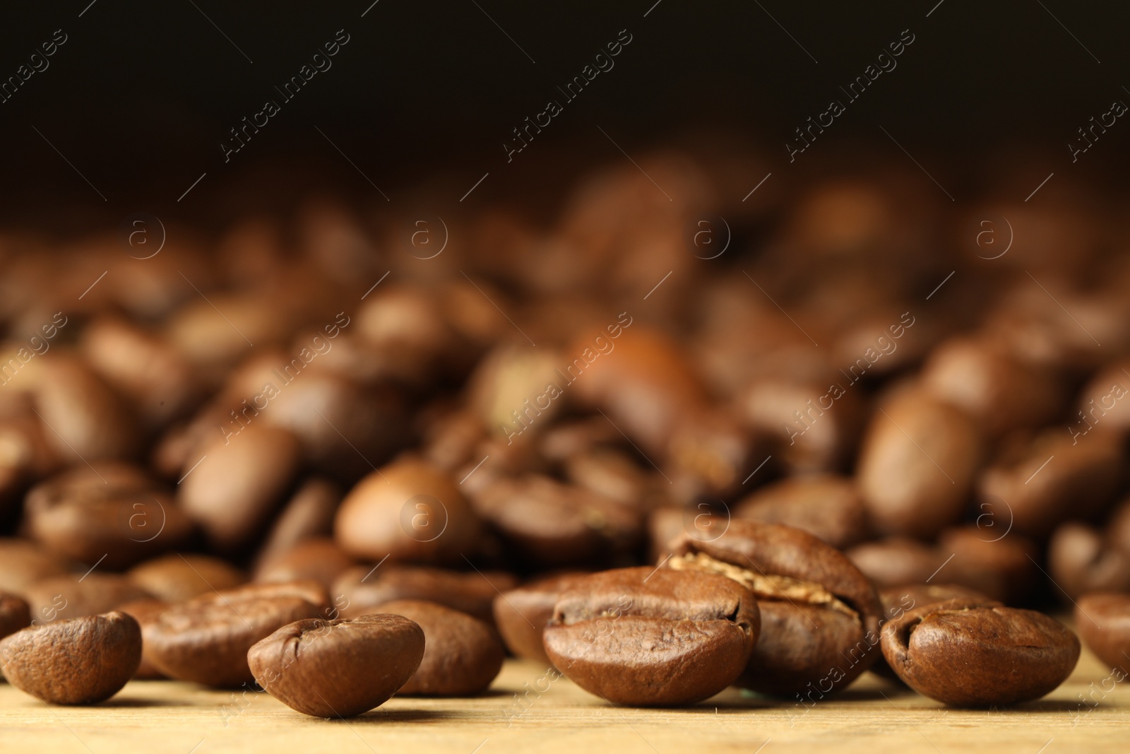 Photo of Many roasted coffee beans on wooden table, closeup