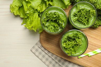 Green smoothie of lettuce leaves in glasses on white wooden table, flat lay. Space for text