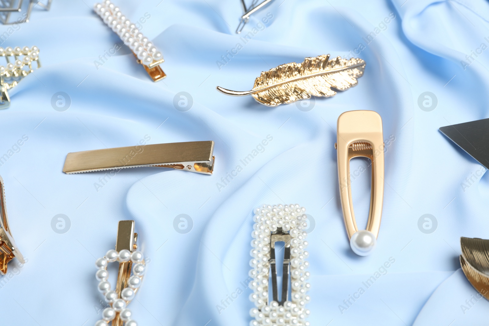 Photo of Stylish hair clips on light blue fabric, above view