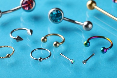Photo of Stylish piercing jewelry on light blue background, closeup
