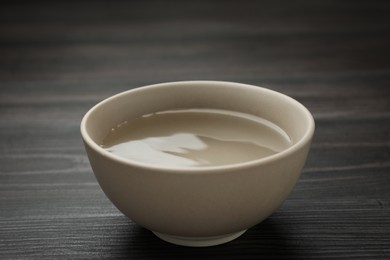 Beige bowl with water on dark wooden table
