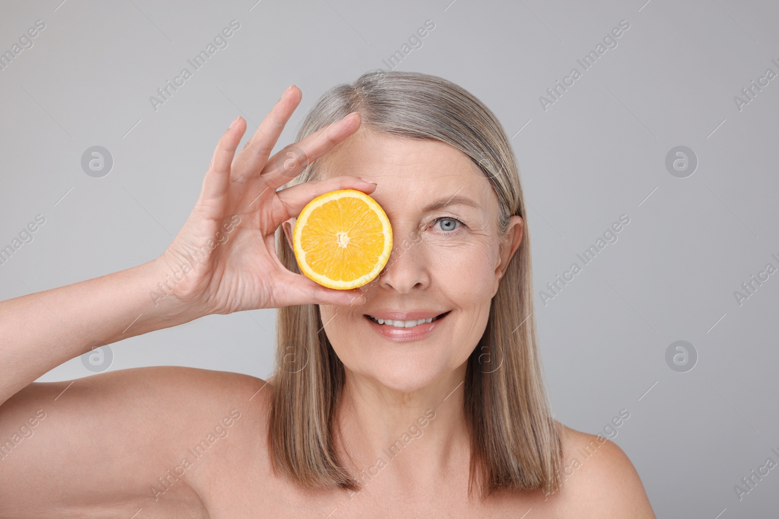 Photo of Beautiful woman with half of orange rich in vitamin C on grey background