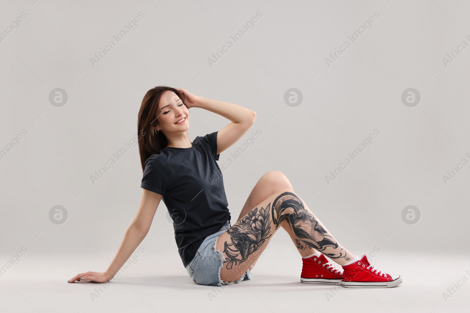 Photo of Smiling tattooed woman posing on grey background