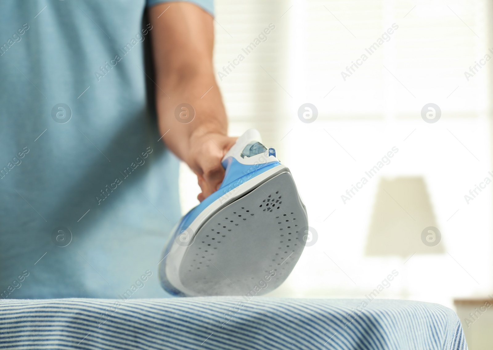 Photo of Handsome man ironing clean laundry at home, closeup