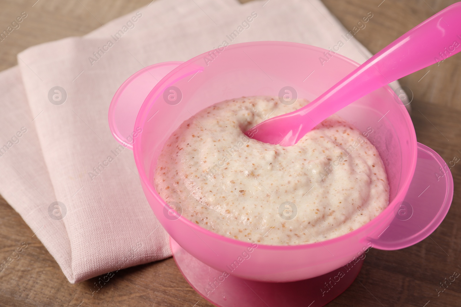 Photo of Baby food. Puree and spoon in bowl on wooden table