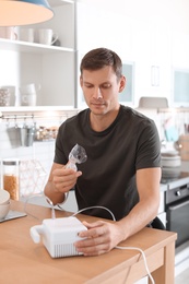 Man using asthma machine at table in kitchen