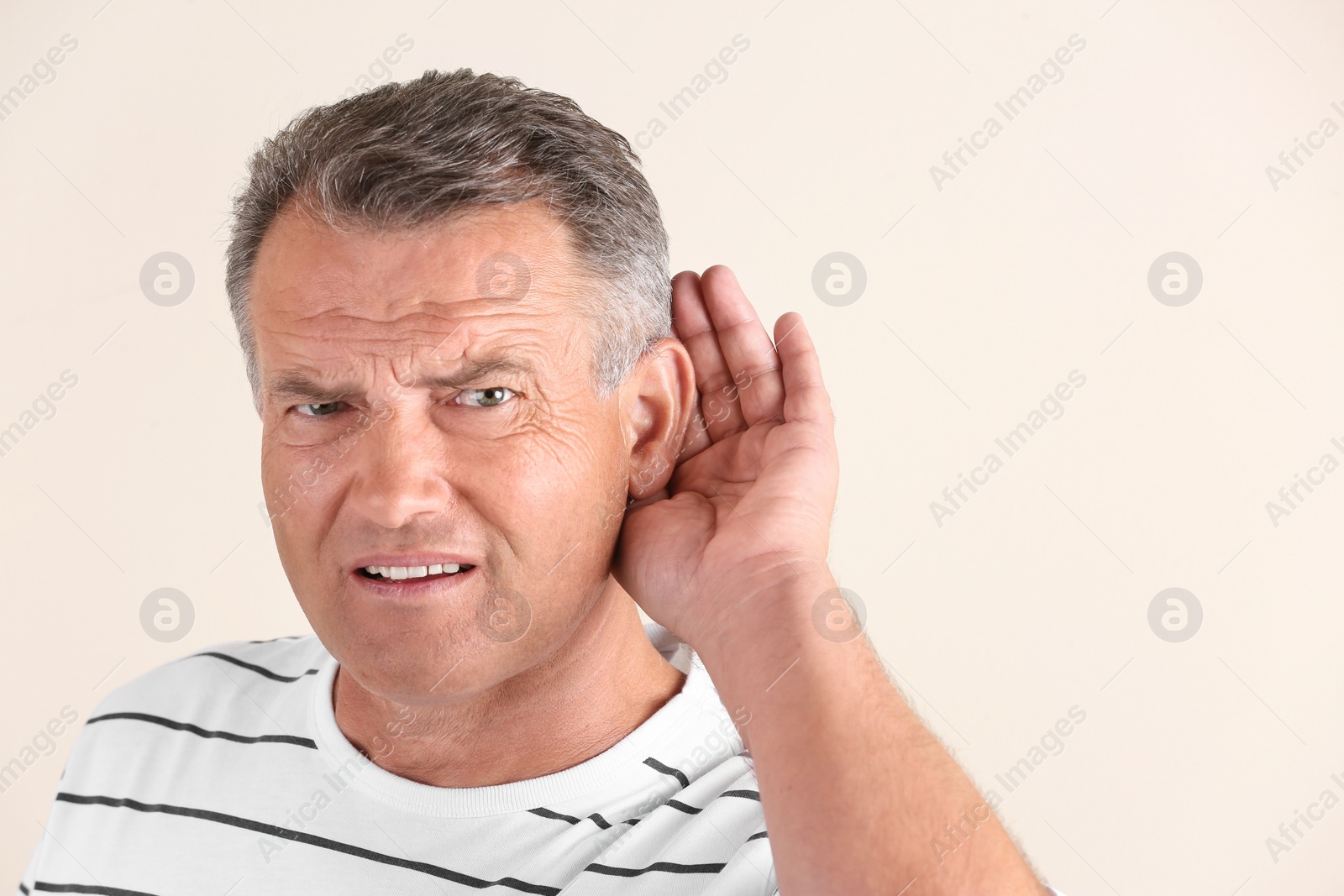 Photo of Mature man with hearing problem on light background