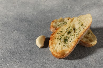Photo of Tasty baguette with garlic and dill on grey textured table, closeup. Space for text