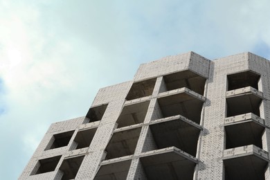 Photo of Construction site with unfinished building under cloudy sky, low angle view