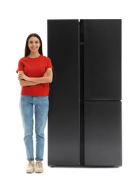Young woman near refrigerator on white background